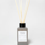 Topgana Canyon reed diffuser in a gray bottle with black cap and several reeds