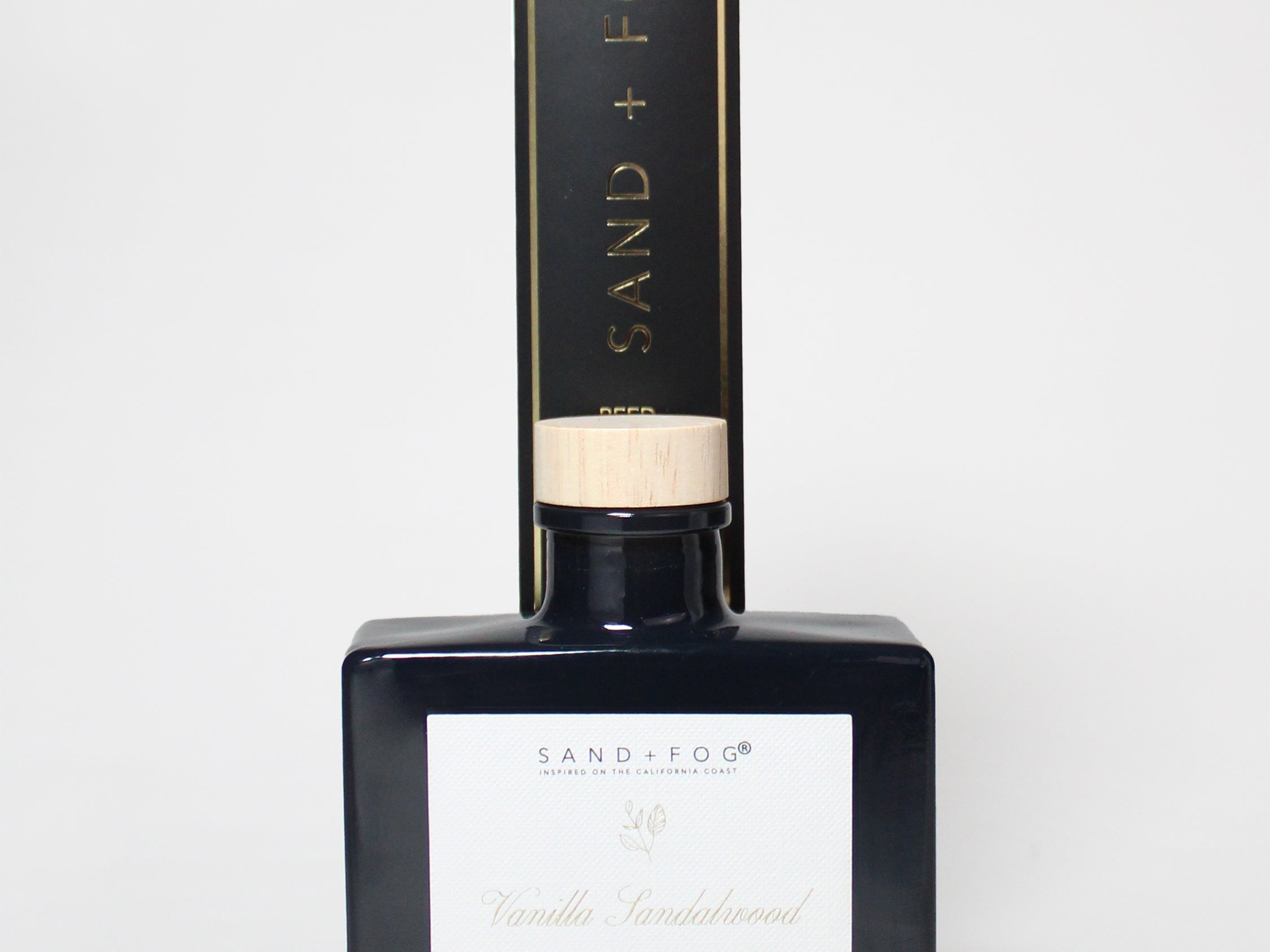 Vanilla sandalwood reed diffuser in a dark glass bottle with a light wood cap and box.