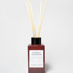 Jasmine & Cedarwood reed diffuser in a burgundy bottle with a black cap and several reeds.