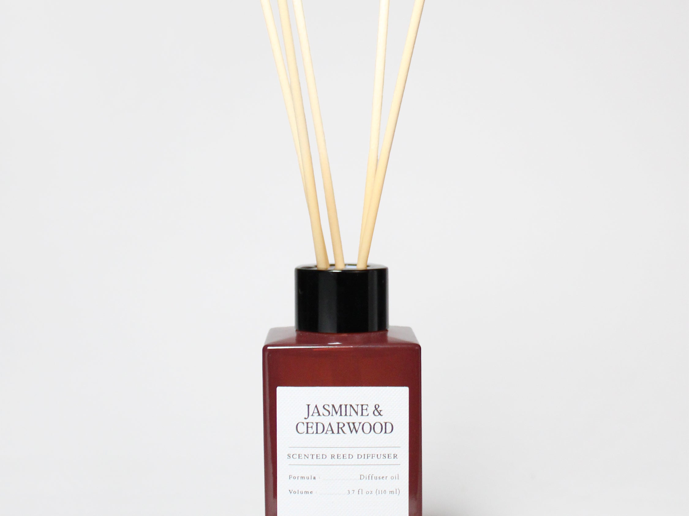 Jasmine & Cedarwood reed diffuser in a burgundy bottle with a black cap and several reeds.