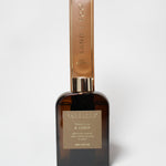 Vanilla and amber reed diffuser in an amber glass bottle with a tall gold-toned carton.