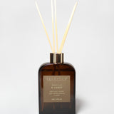 Vanilla and amber reed diffuser in a dark amber glass bottle with pale reeds.