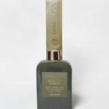 Bergamot and neroli reed diffuser in a dark green glass bottle with a tall Sand + Fog box.
