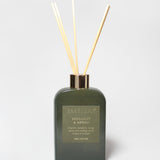 Bergamot and neroli reed diffuser in a dark green glass bottle with four reeds.