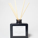 Vanilla sandalwood reed diffuser in a dark glass bottle with five natural reeds.