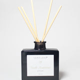 Vanilla sandalwood reed diffuser in a dark glass bottle with five natural reeds.