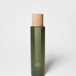 Green glass room spray bottle with cork stopper and measurement text on front