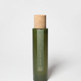 Green glass room spray bottle with cork stopper and measurement text on front