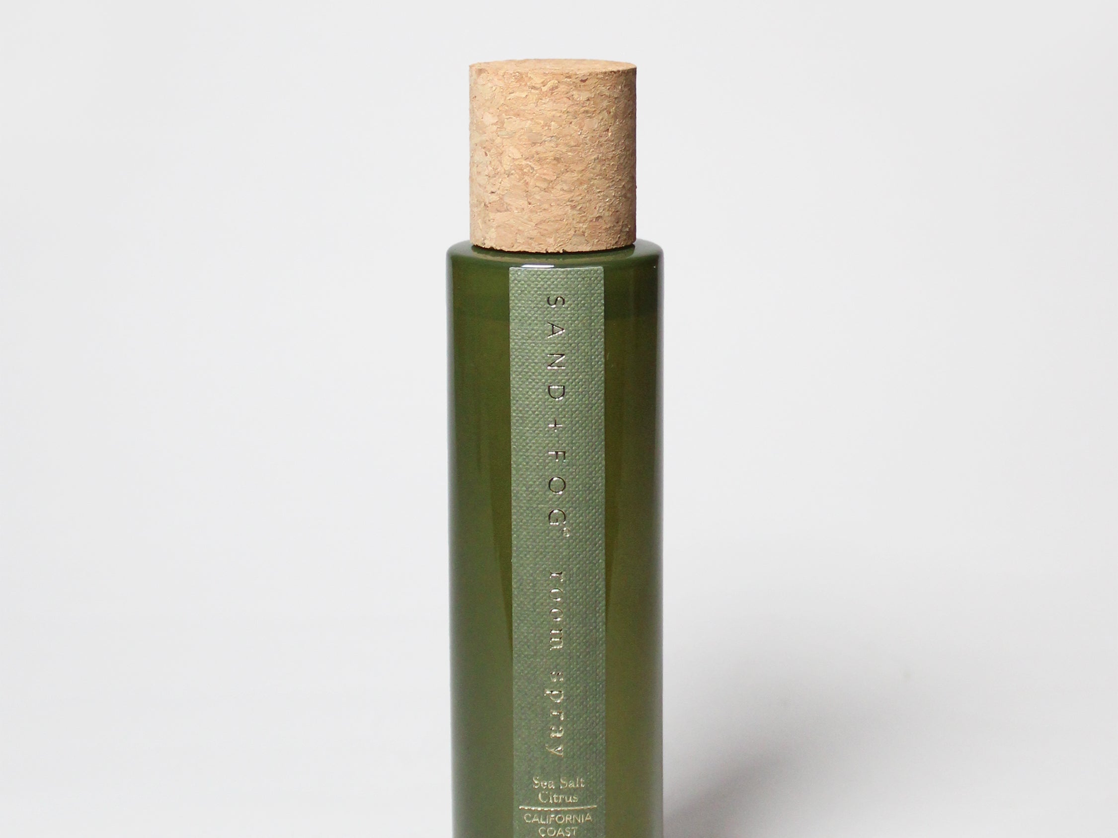 Green glass room spray bottle with cork stopper and measurement text on front