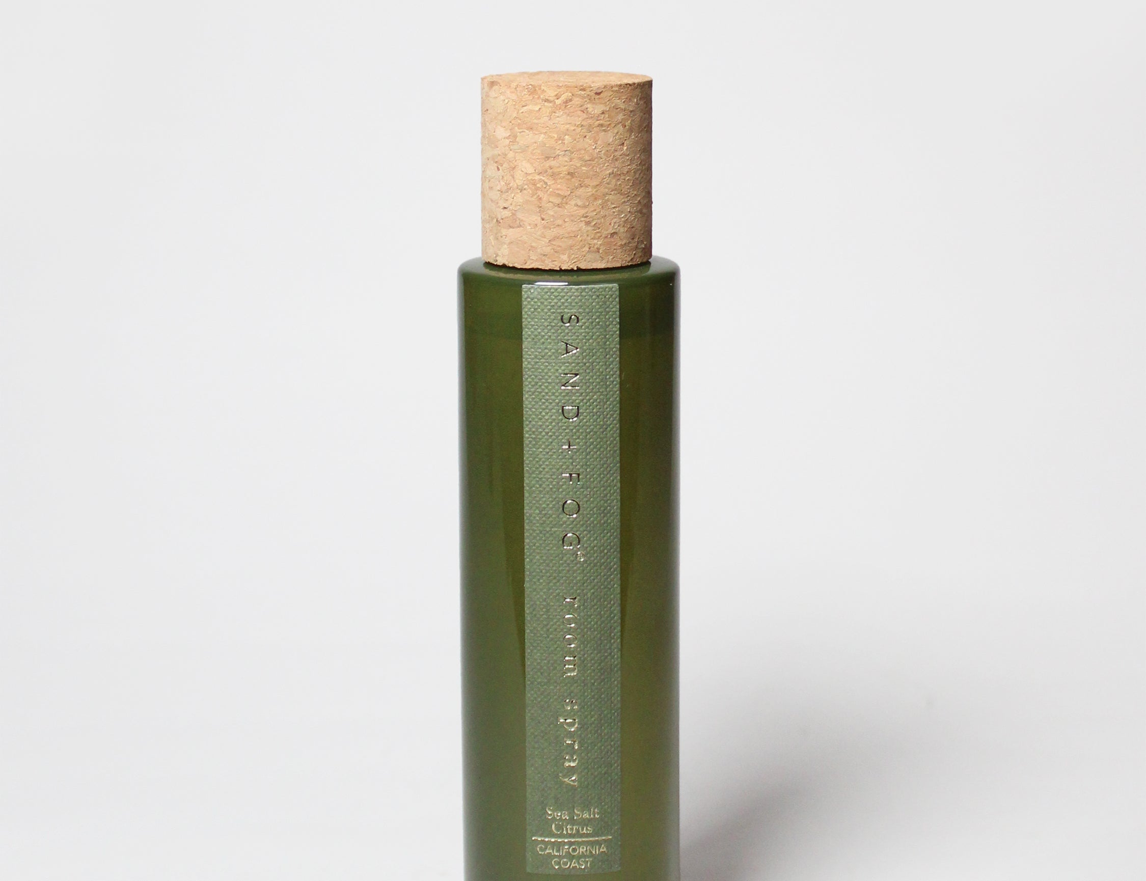 Green glass room spray bottle with cork stopper and measurement text on front