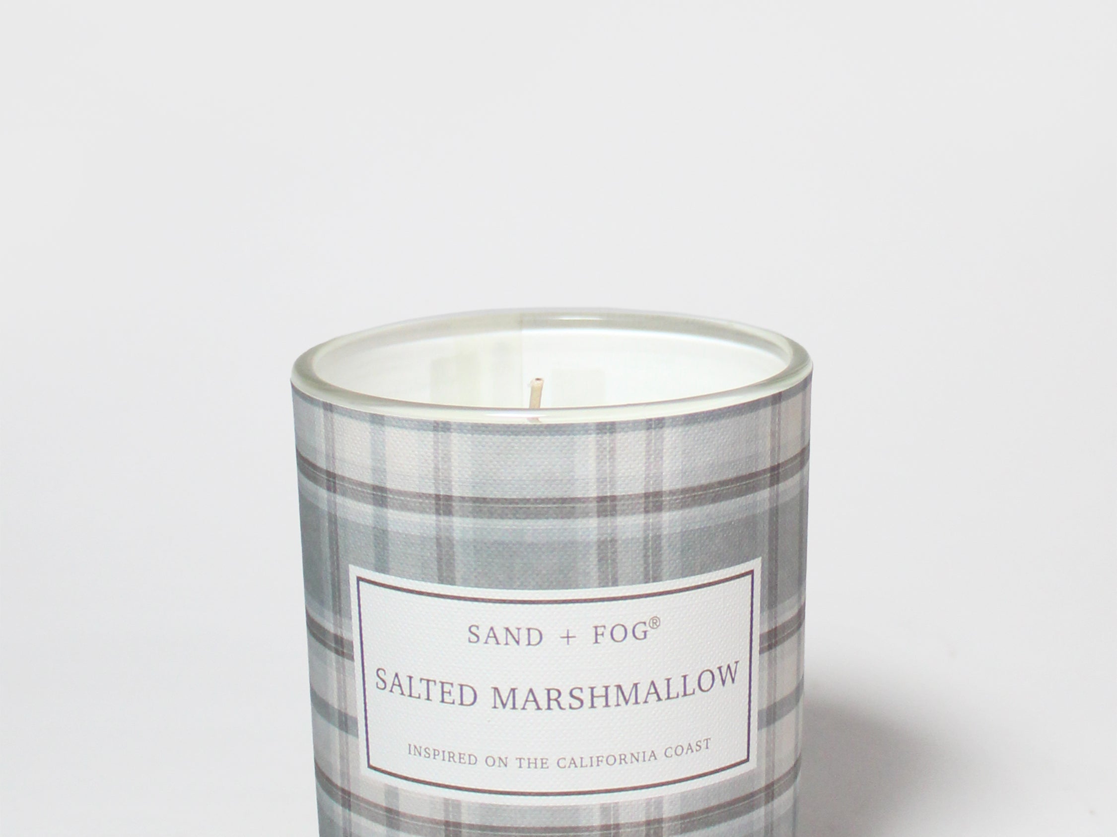 Salted Marshmallow scented candle in a clear glass jar with a gray plaid label and visible wick.