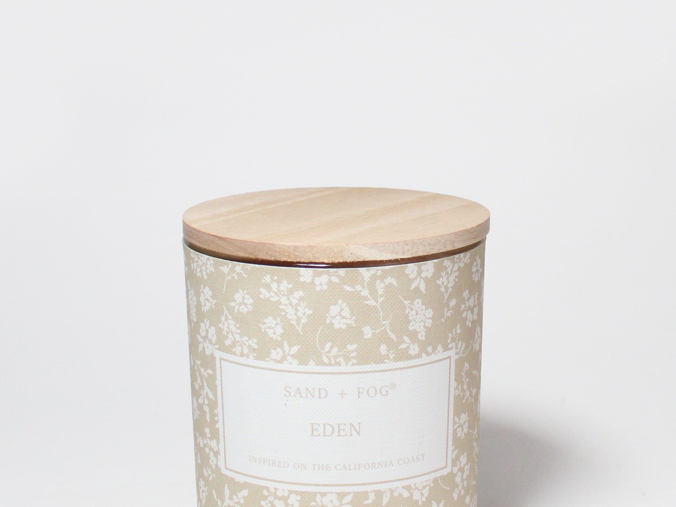 Eden 10 oz scented candle in a beige floral-patterned glass jar with a wooden lid.