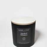 Black scented candle with lid and “Sand + Fog” Smoked Whiskey label, 21 oz jar
