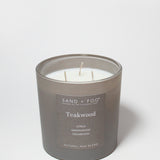 Teakwood scented candle in dark gray jar with three wicks and printed label