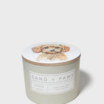 Scented candle jar with dog portrait lid and Sand + Paws Amber Skies label