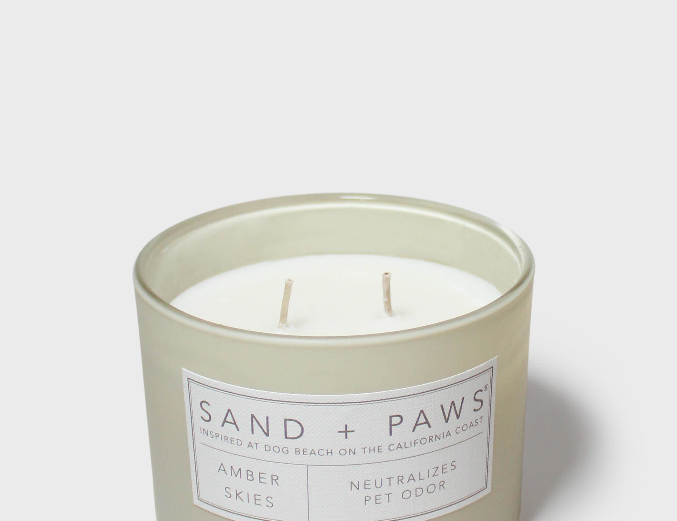 Amber Skies scented candle in frosted glass, Sand + Paws label on jar