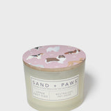 Scented candle with pink dog-print lid and Sand + Paws label