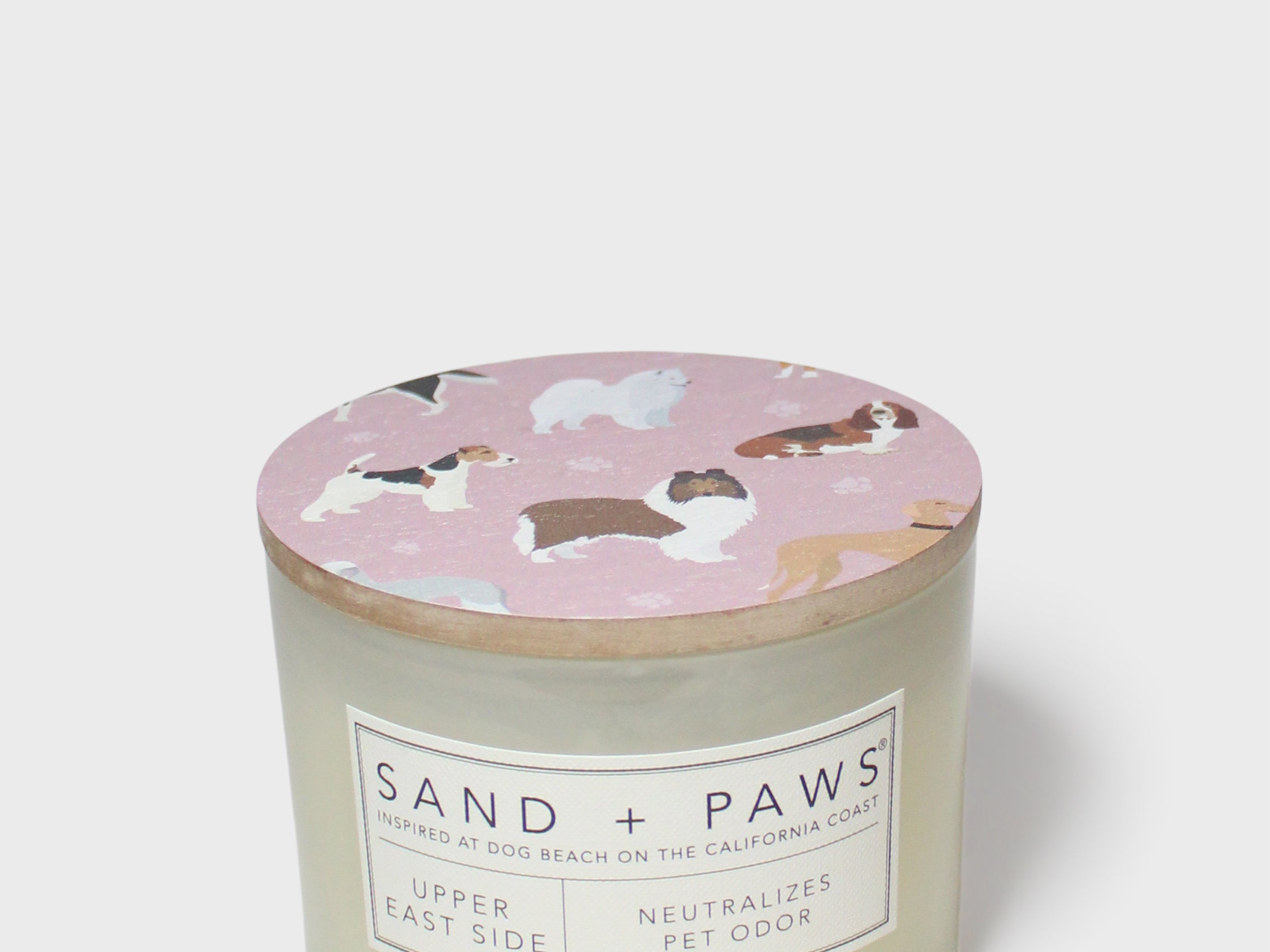 Scented candle with pink dog-print lid and Sand + Paws label