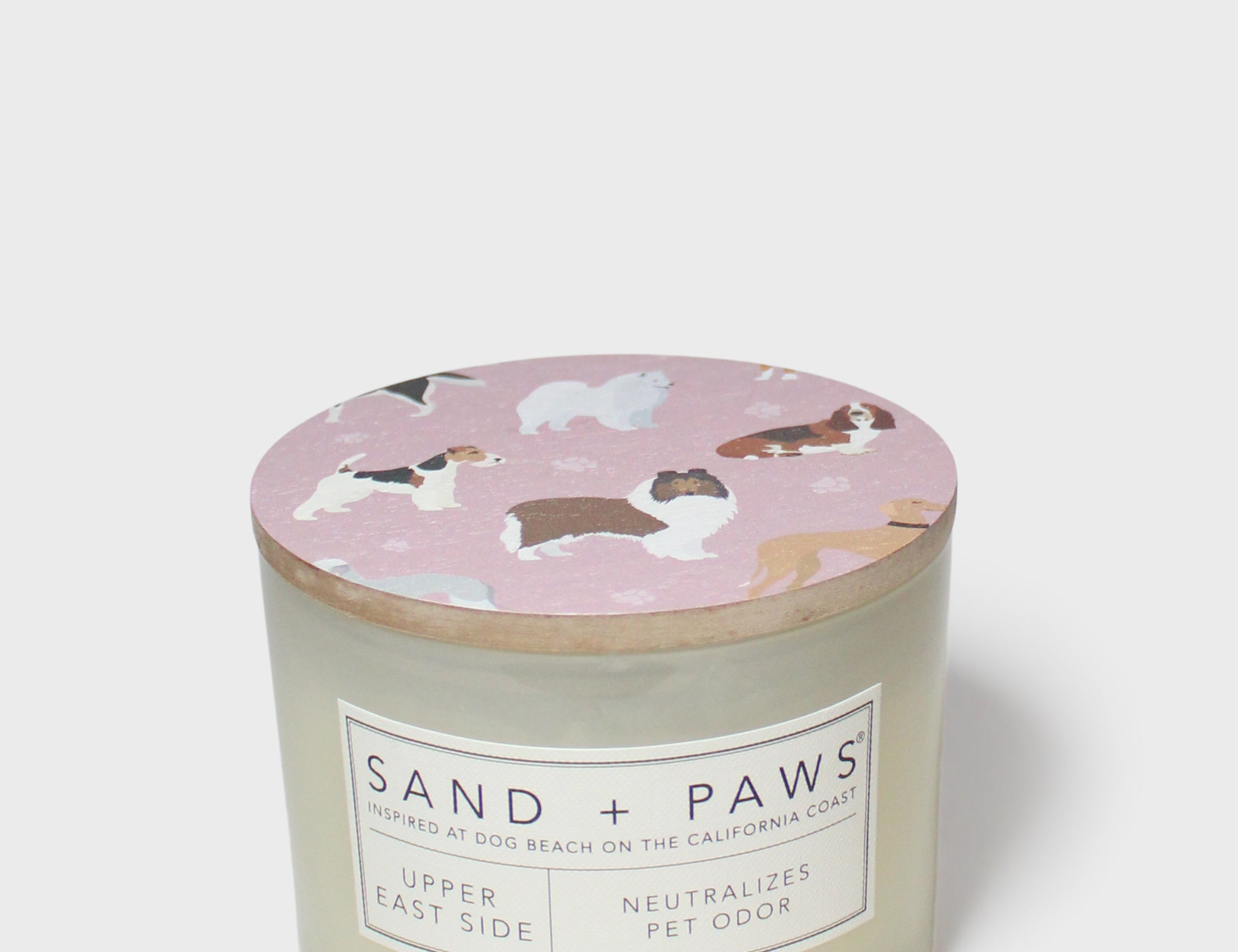 Scented candle with pink dog-print lid and Sand + Paws label