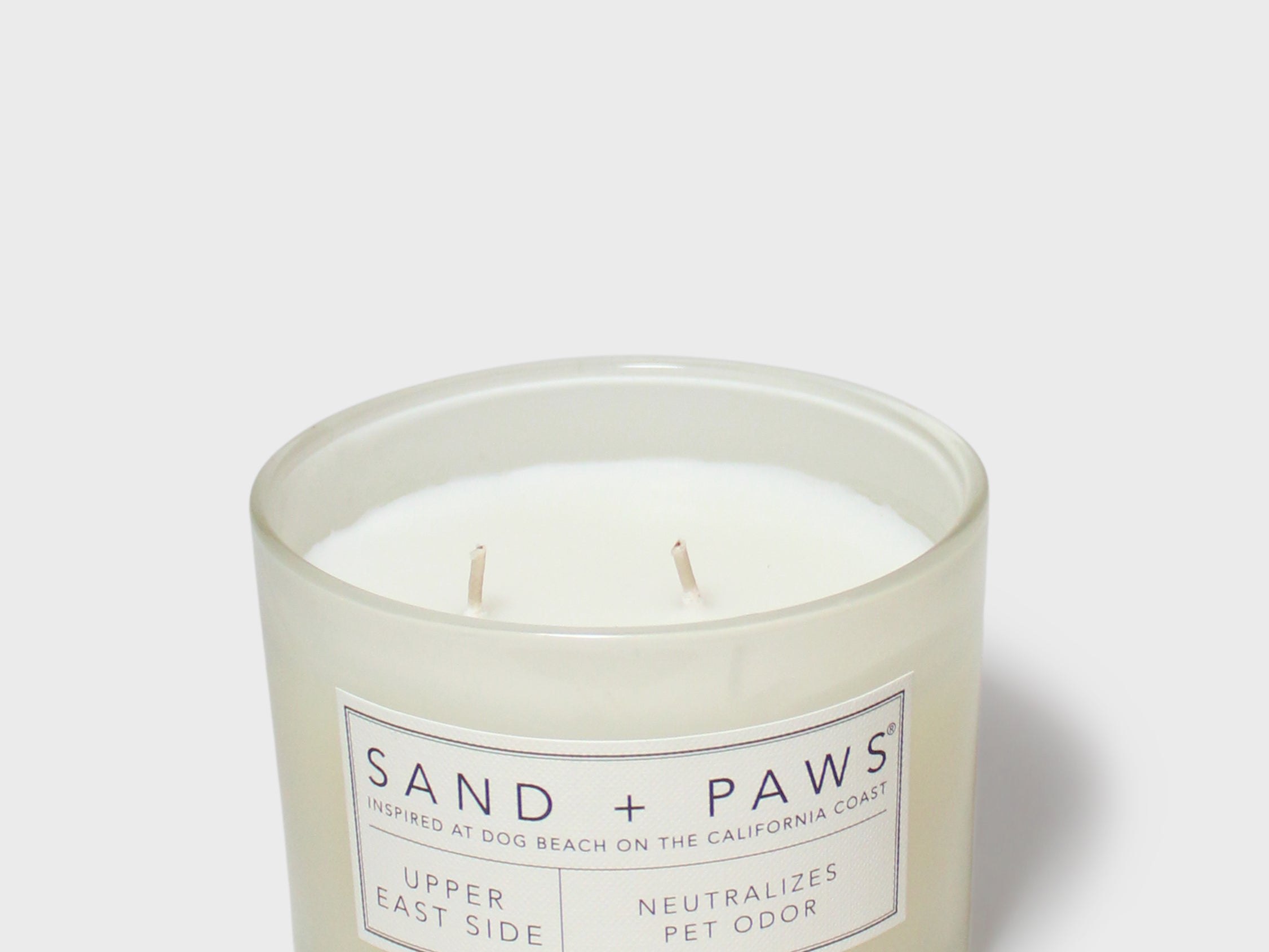 Scented candle in clear jar with Sand + Paws label and twin wicks