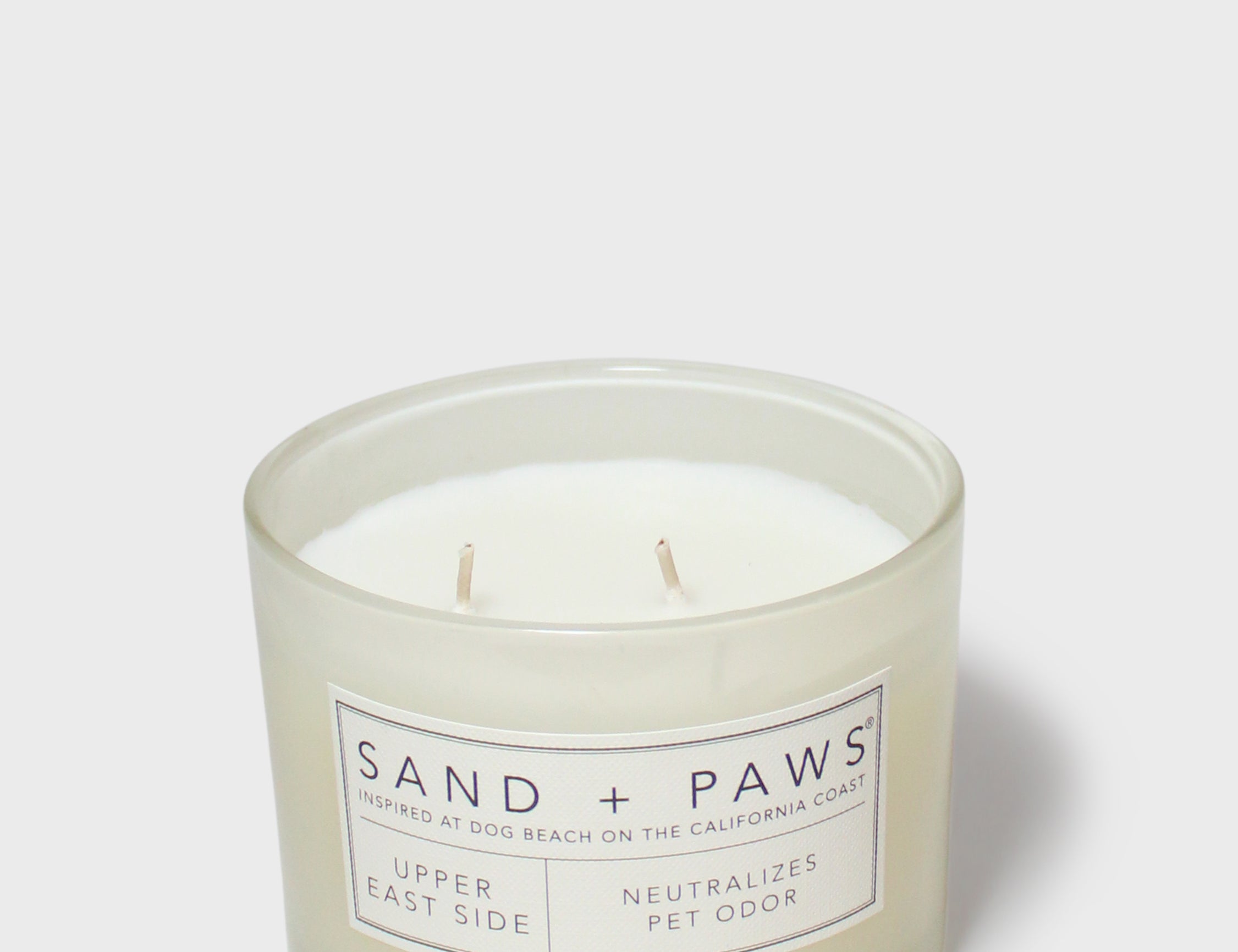 Scented candle in clear jar with Sand + Paws label and twin wicks