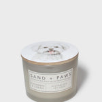 Sand + Paws scented candle jar with dog-portrait lid and cream 'SAND + PAWS' label