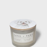 Sand + Paws scented candle jar with dog-portrait lid and cream 'SAND + PAWS' label