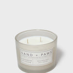 Sand + Paws scented candle jar with cream wax, two wicks, 'SAND + PAWS' label