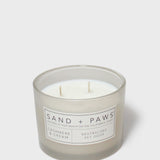 Sand + Paws scented candle jar with cream wax, two wicks, 'SAND + PAWS' label