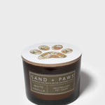 12 oz scented candle in dark glass jar with white lid and paw print emblem.