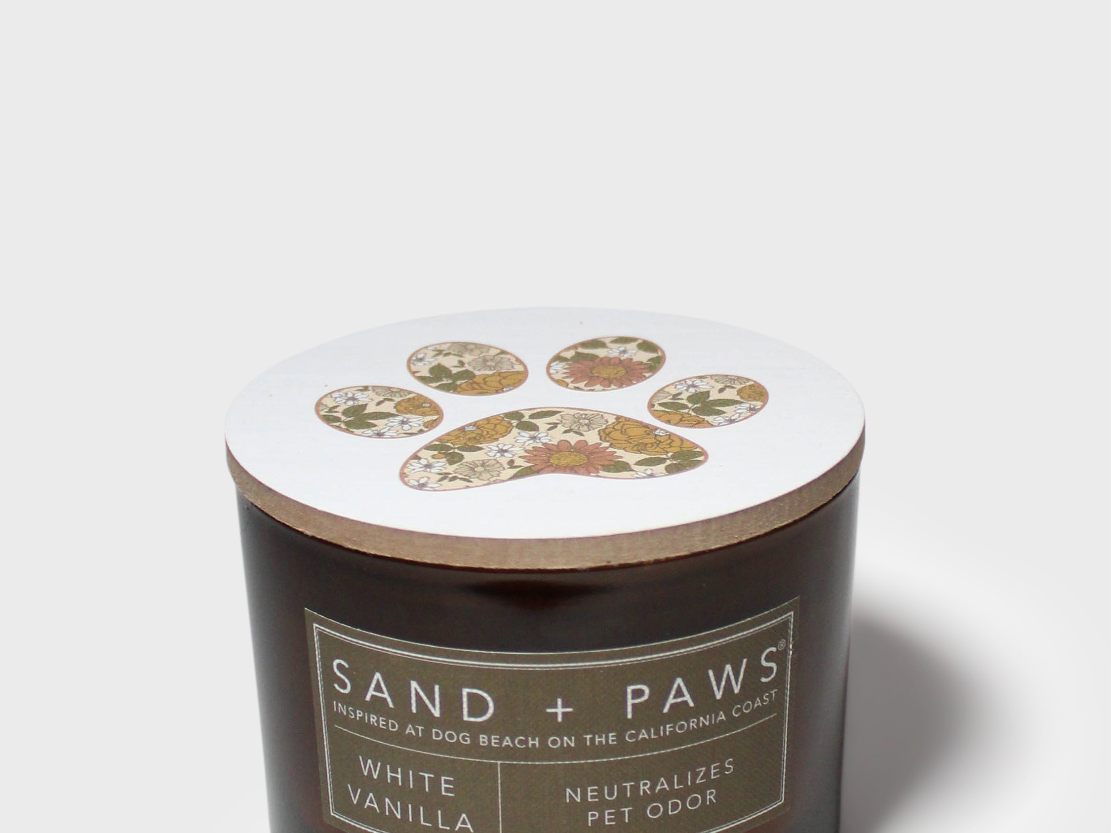 12 oz scented candle in dark glass jar with white lid and paw print emblem.
