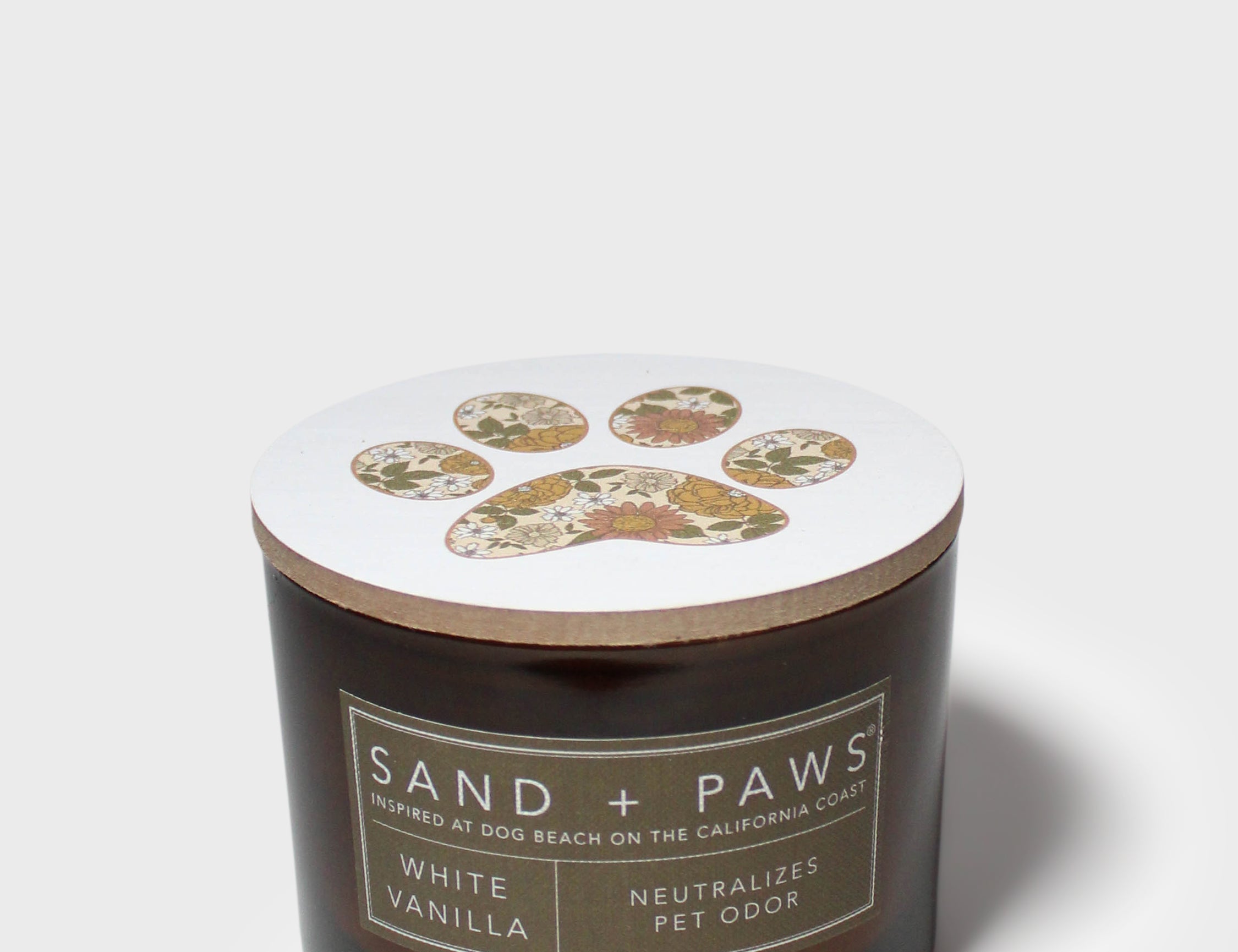 12 oz scented candle in dark glass jar with white lid and paw print emblem.