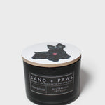 Black jar scented candle with dog graphic lid and Sand + Paws label