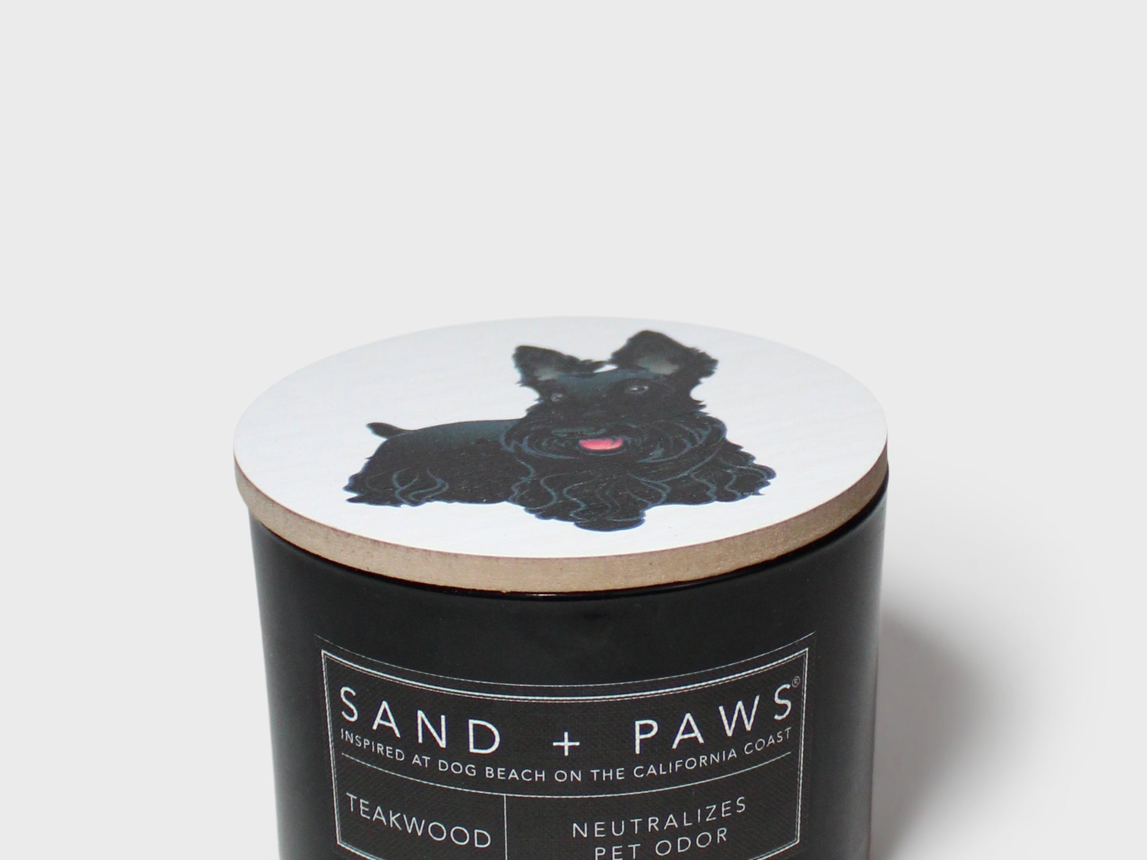 Black jar scented candle with dog graphic lid and Sand + Paws label