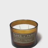 Sand + Paws vanilla scented candle in dark glass jar, wicks visible.
