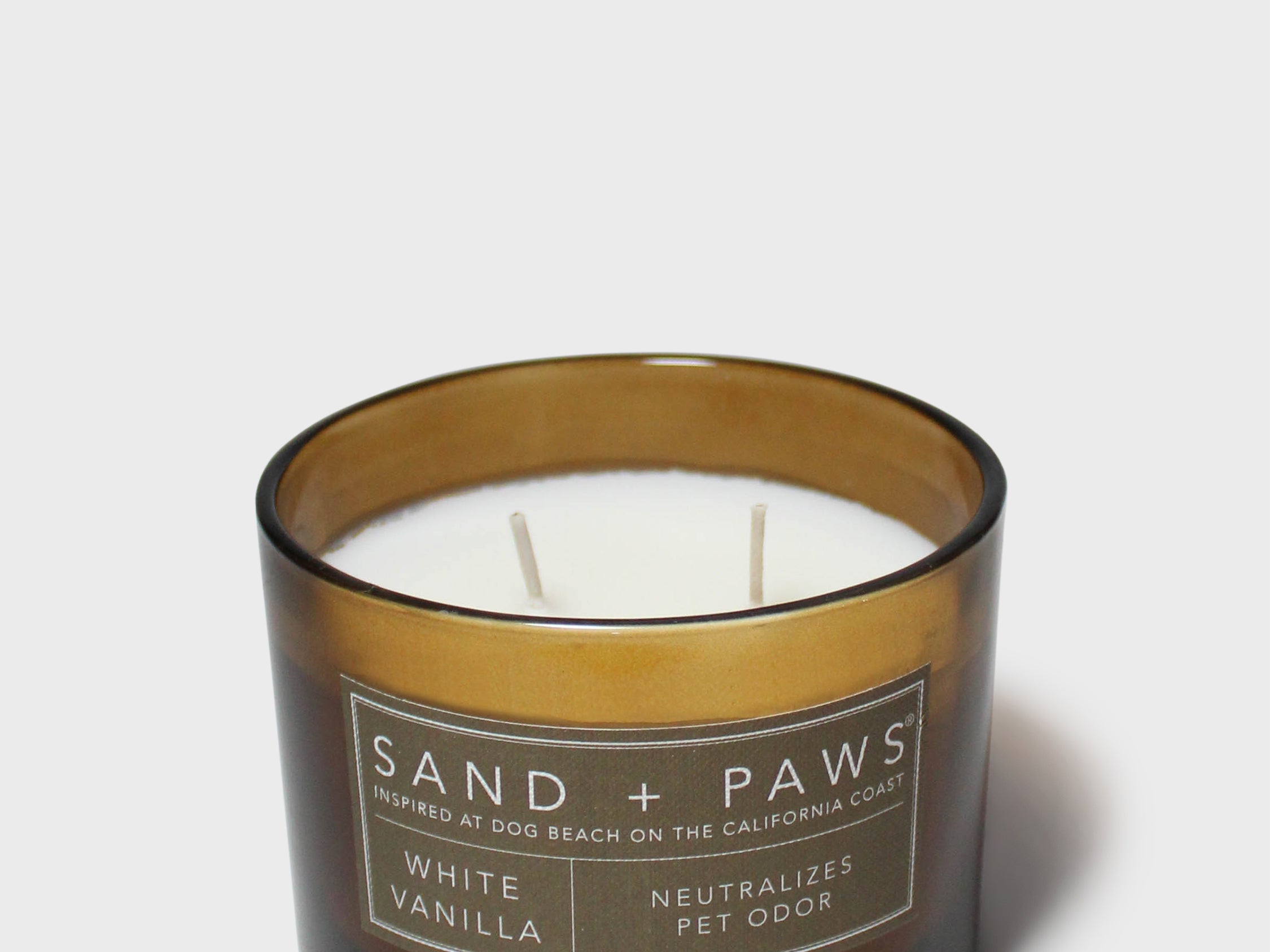 Sand + Paws vanilla scented candle in dark glass jar, wicks visible.