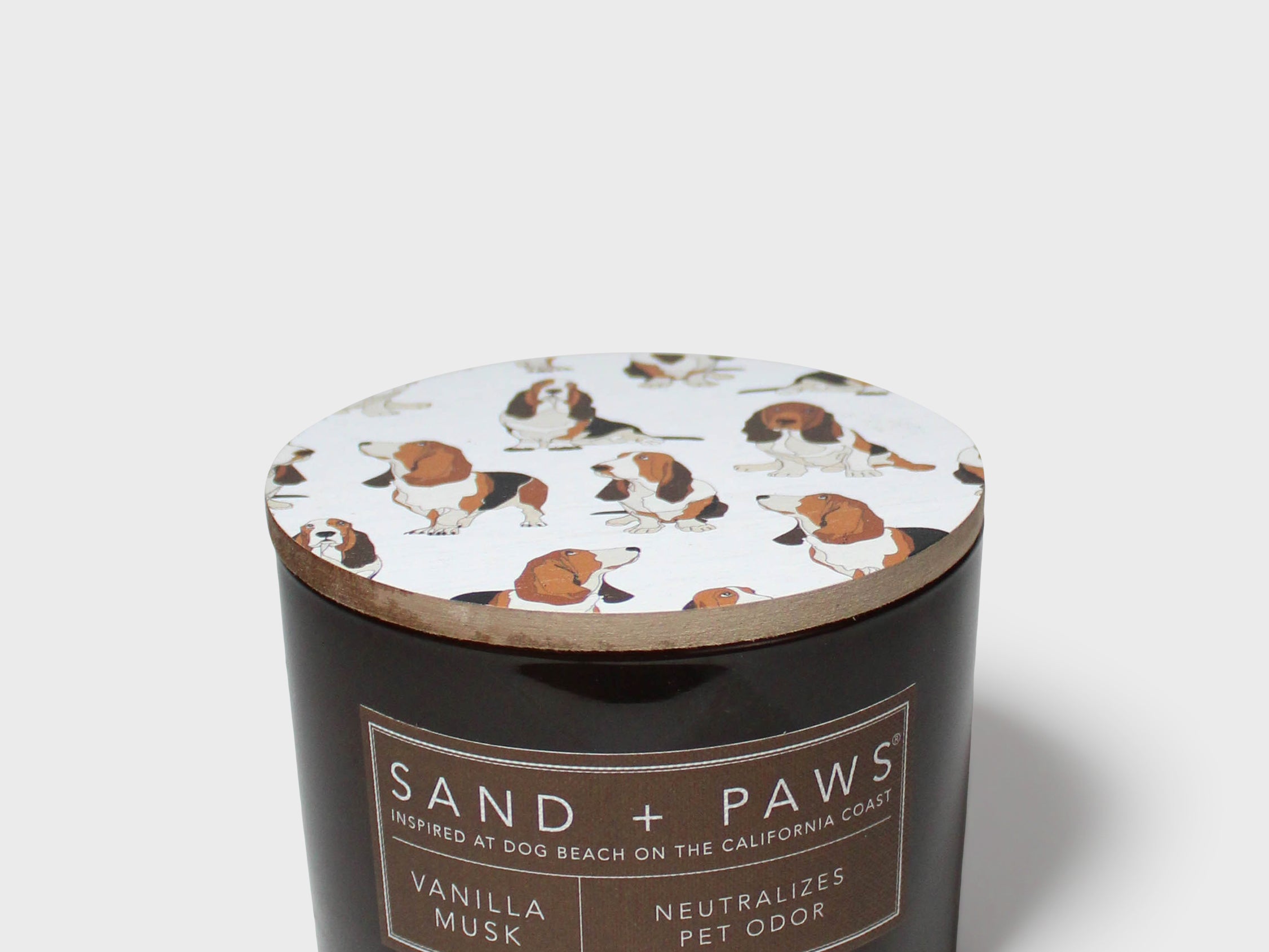 Scented candle in dark glass jar with Sand + Paws label and printed dog lid
