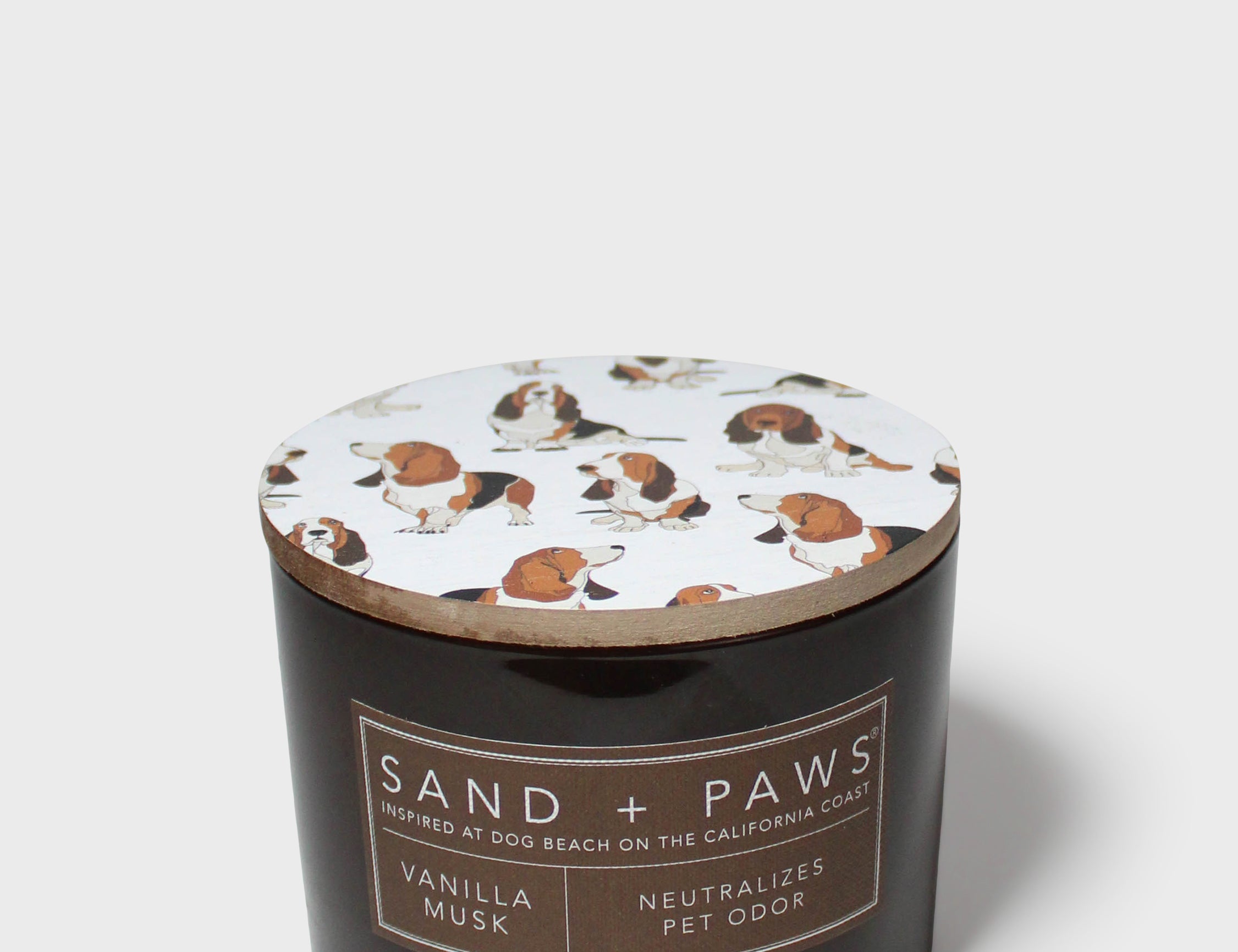 Scented candle in dark glass jar with Sand + Paws label and printed dog lid