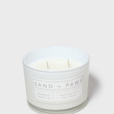 Scented candle in white glass jar with two wicks and orange vanilla label