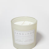 Scented candle tin with 'Sand + Fog' label and two wicks