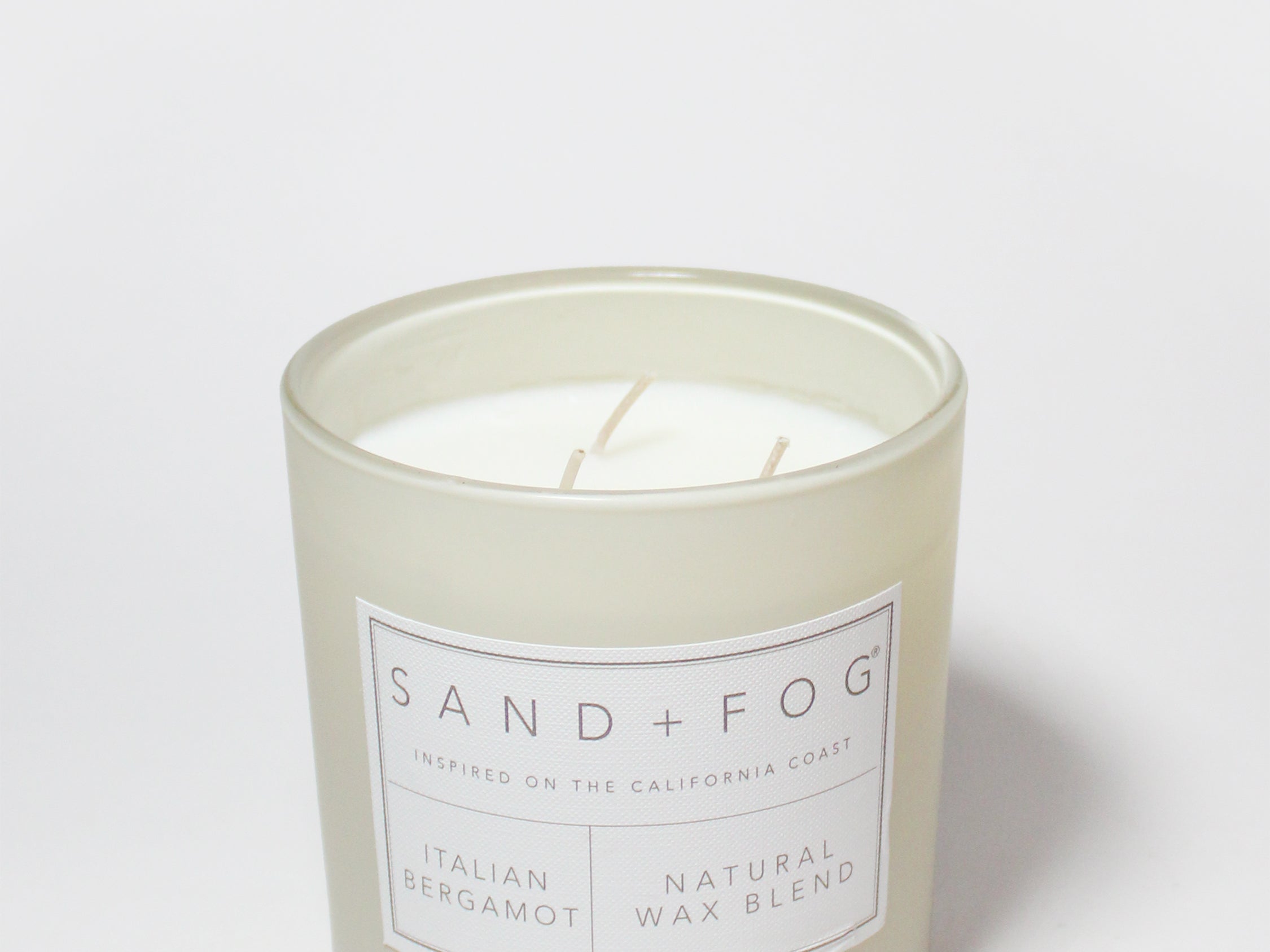 Scented candle tin with 'Sand + Fog' label and two wicks
