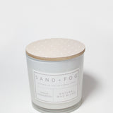Scented candle with speckled beige lid and white label on jar