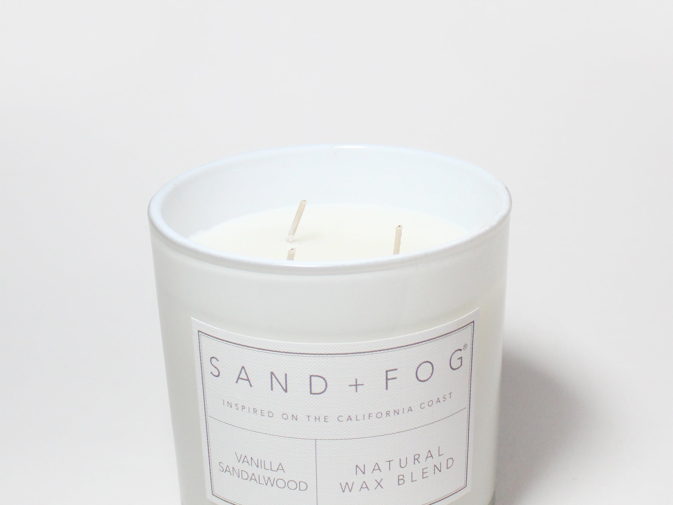 Vanilla sandalwood scented candle in white jar with label; natural wax blend