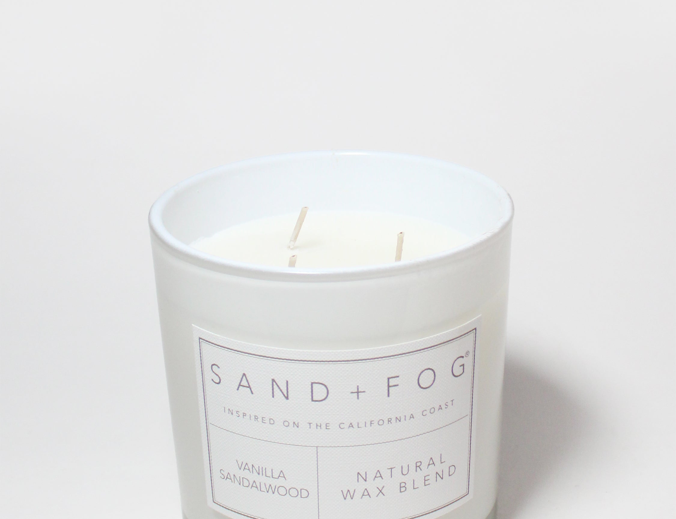 Vanilla sandalwood scented candle in white jar with label; natural wax blend