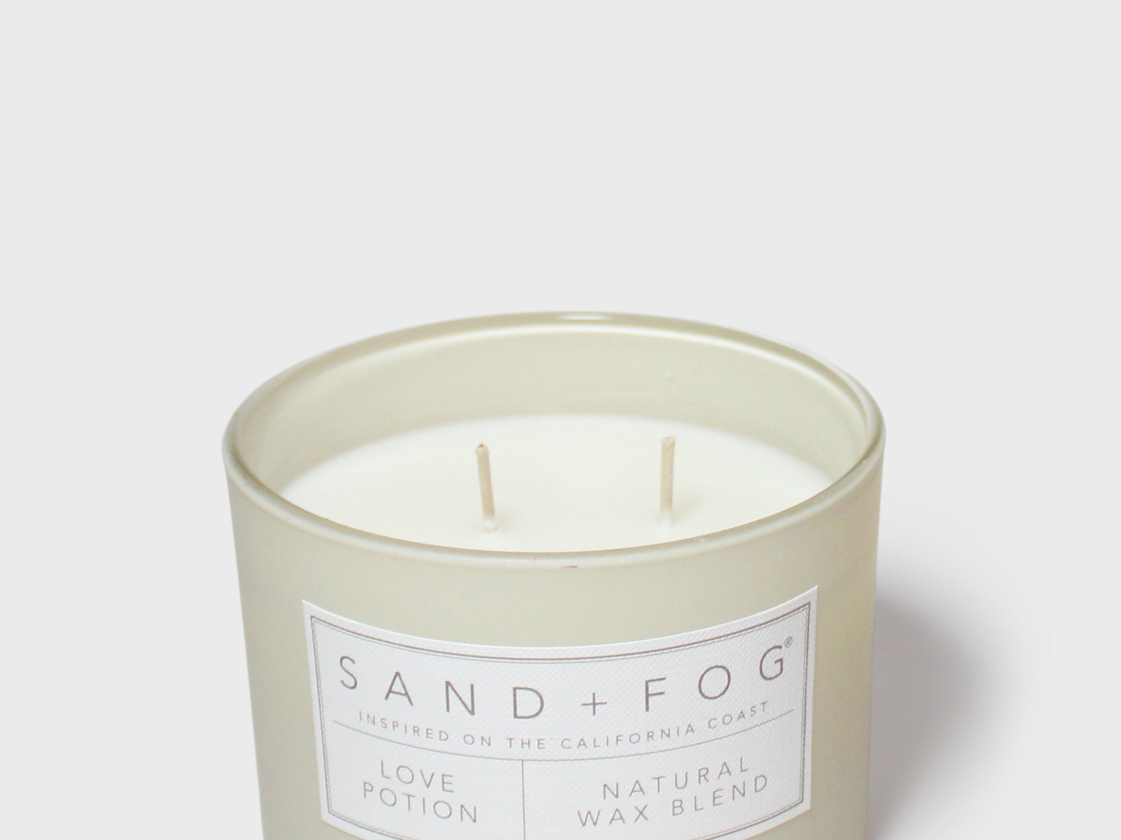 Glass jar scented candle with two wicks and Sand+Fog Love Potion label