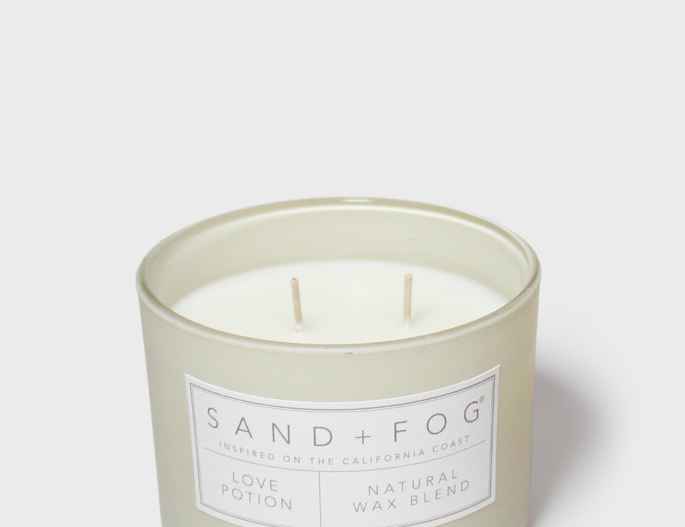 Glass jar scented candle with two wicks and Sand+Fog Love Potion label