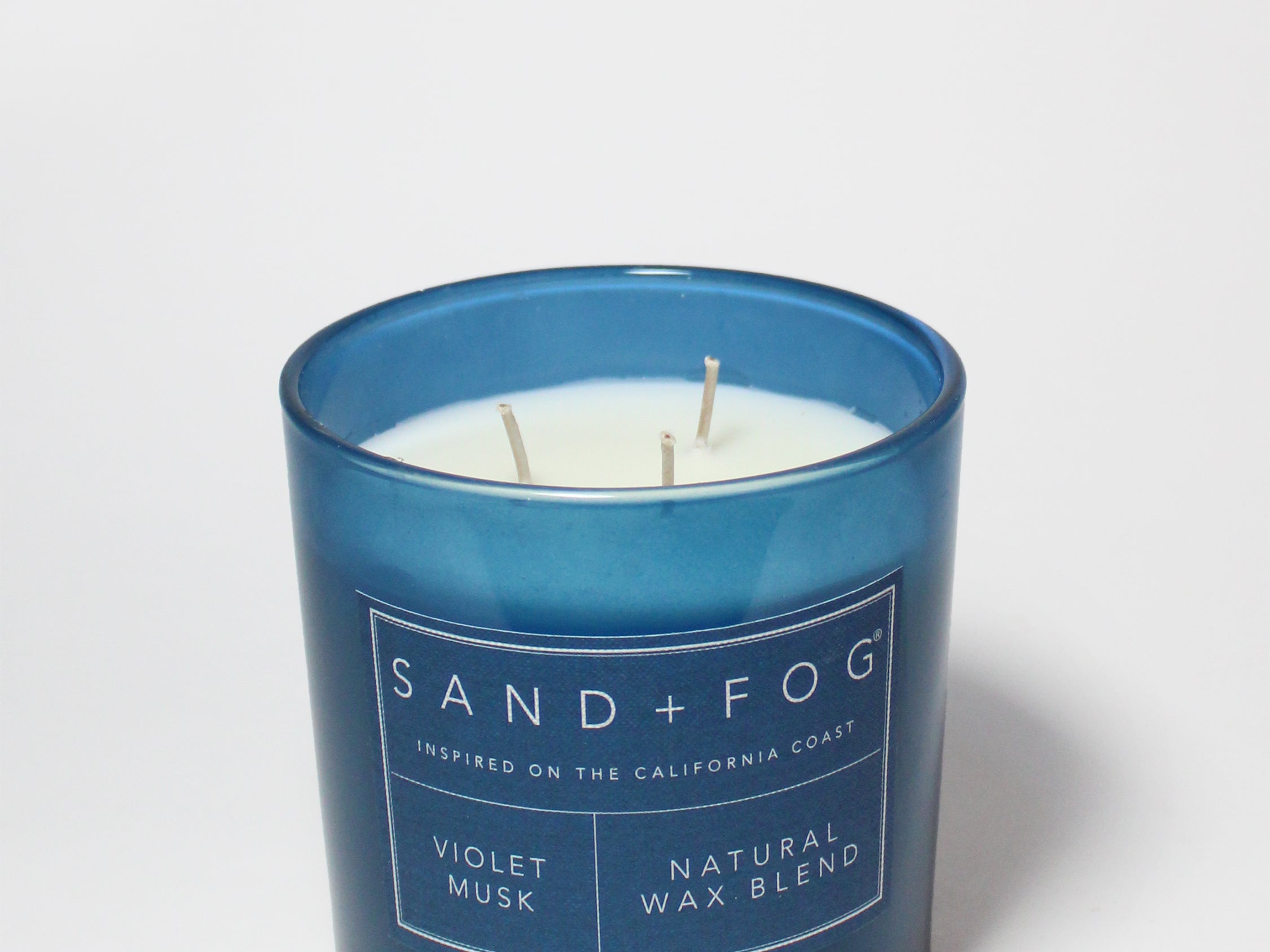 Blue scented candle jar with SAND+FOG label and two wicks