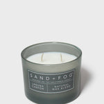 Scented candle in dark glass jar with white label and two visible wicks