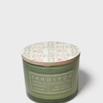Scented soy candle in green glass jar with printed lid and Sand+Fog label
