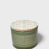 Scented soy candle in green glass jar with printed lid and Sand+Fog label